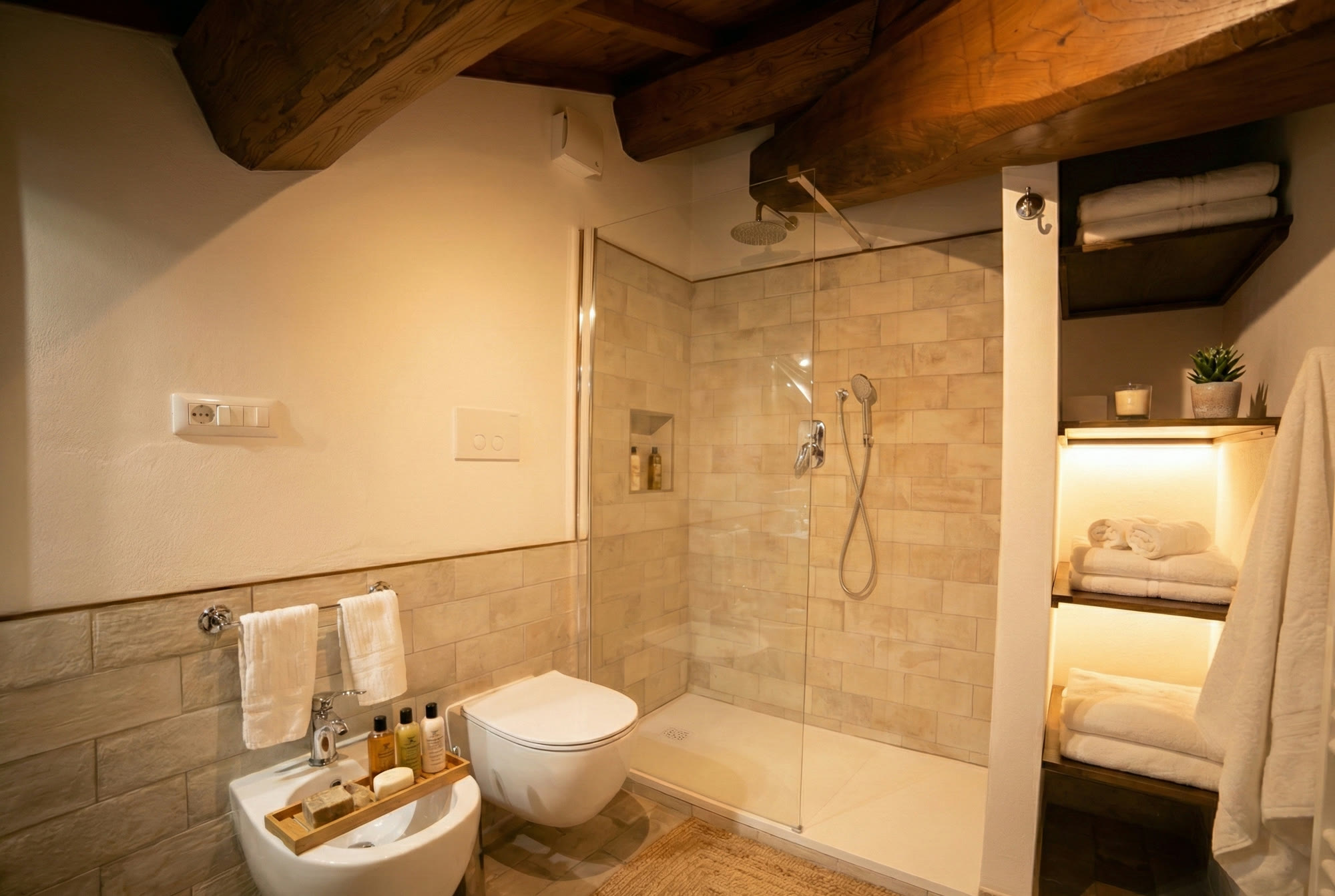 Walk-in shower under sloping beams, towels on lit shelves
